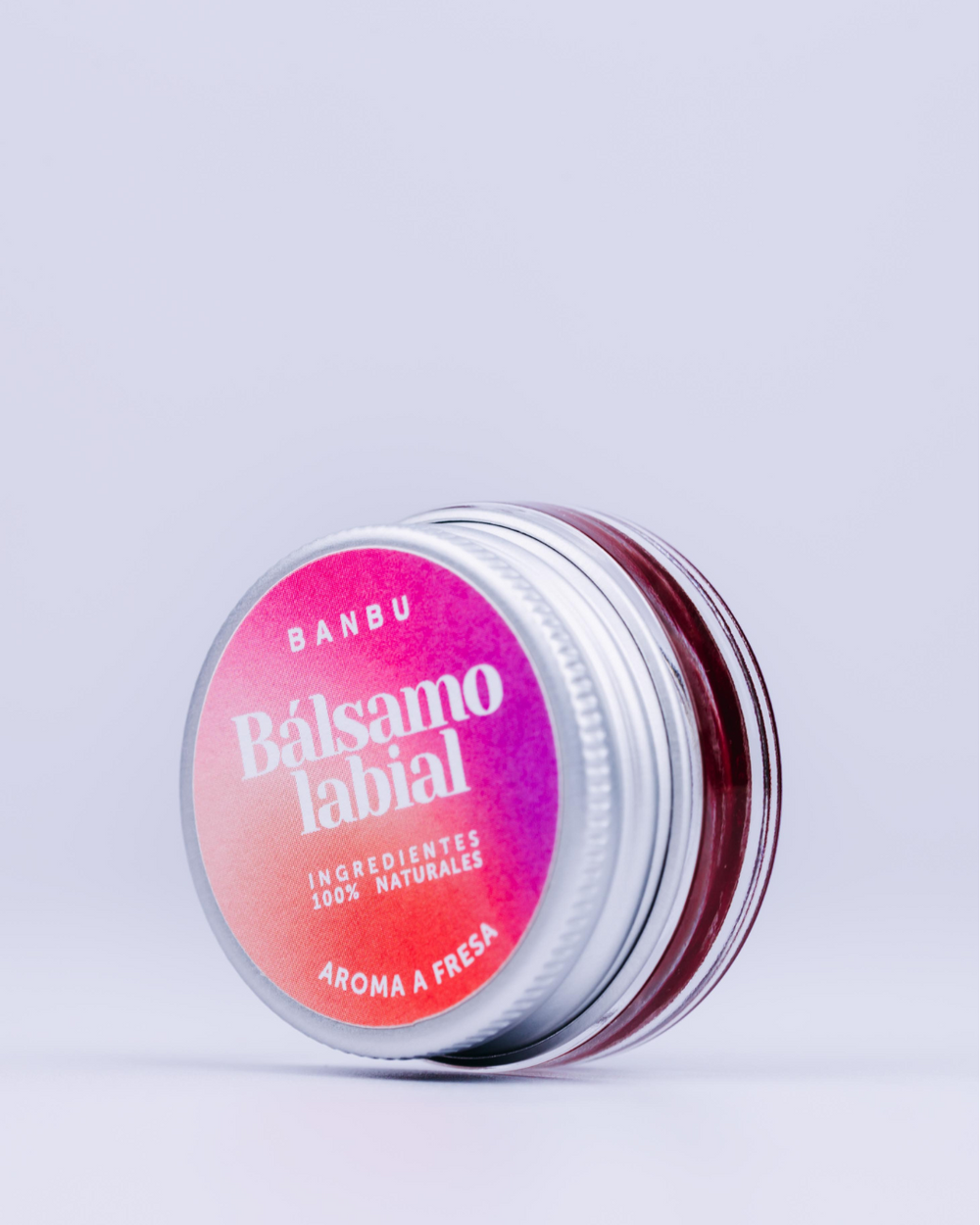 Bálsamo labial con color fresa en tarro de cristal.